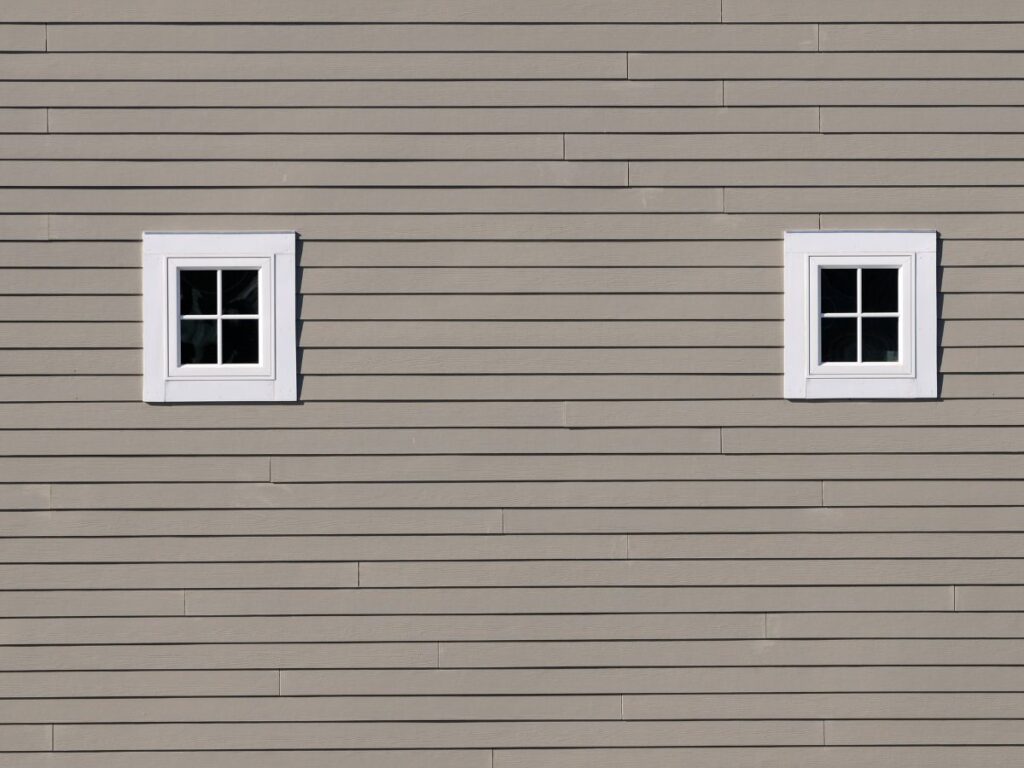 Two small windows set in light gray house siding