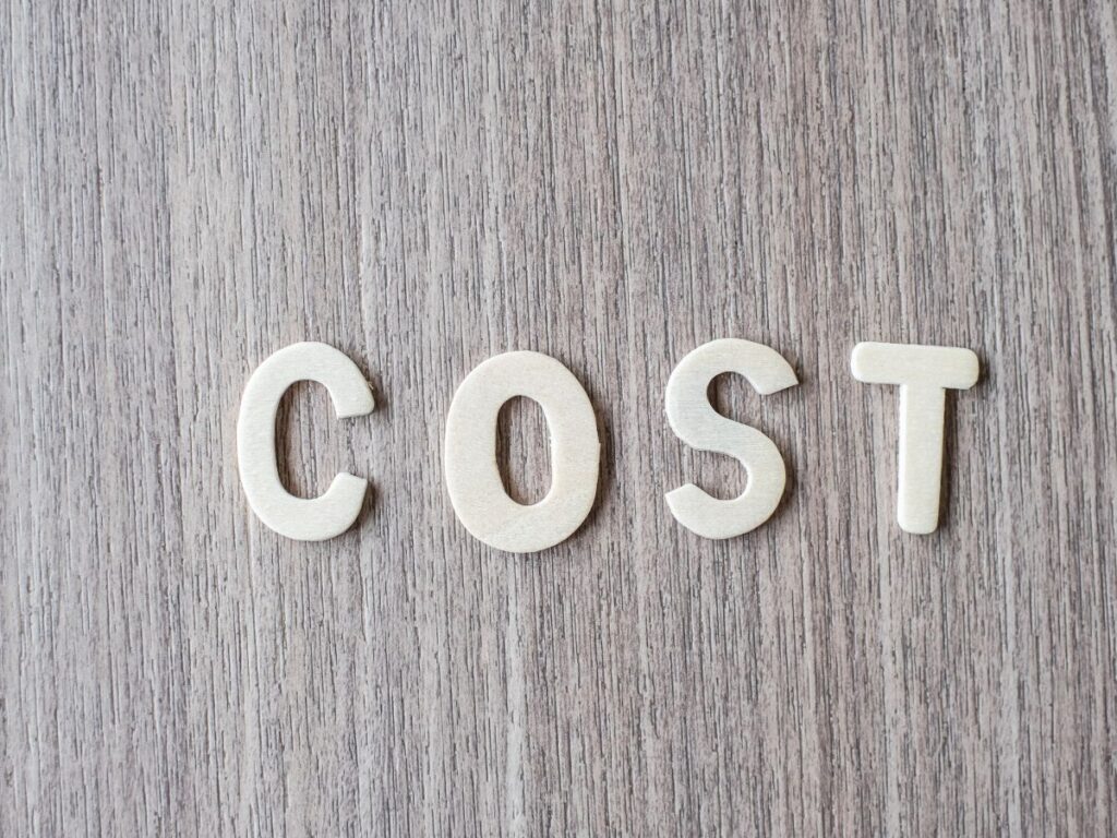 White letters spelling “COST” on a light wood surface