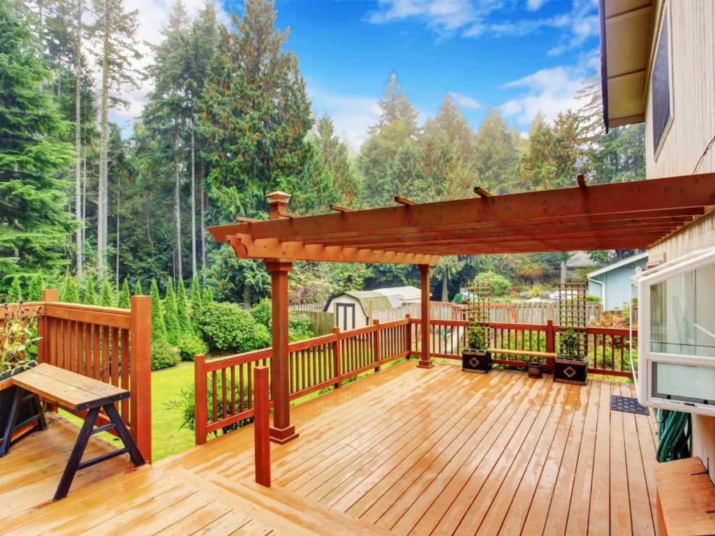 Wooden deck with pergola overlooking a green backyard